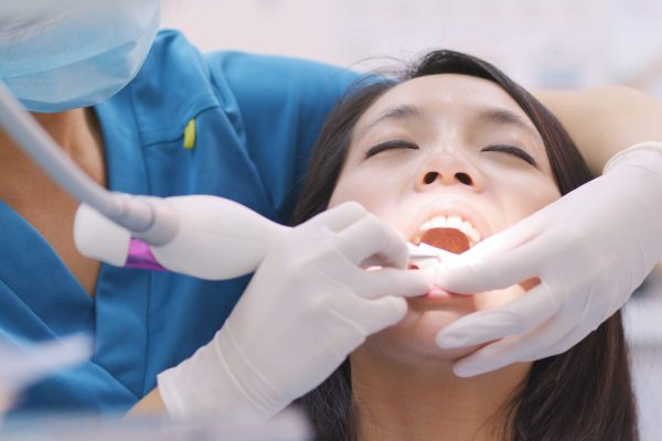 woman doing scaling and root planing in dental cli utc